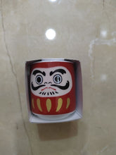 Charger l'image dans la galerie, Petit pot en céramique rouge vif en forme de poupée japonaise Daruma, vu de face sur fond clair

