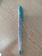 Charger l'image dans la galerie, Stylo roller gel Uni-ball Signo Noble Metal vert métallisé posé à la verticale sur une table en bois clair
