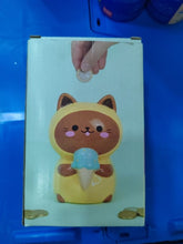 Charger l'image dans la galerie, Tirelire en céramique Balvi Kawaii Minty en forme de chat jaune tenant une glace bleue, vue de face, avec une main insérant une pièce
